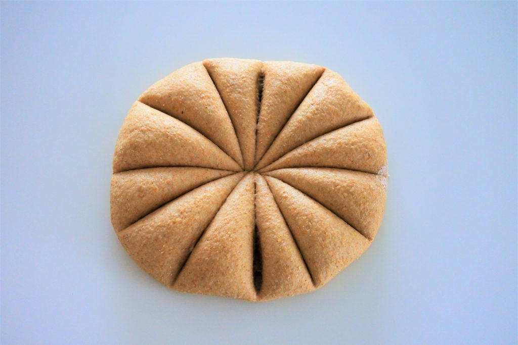 An overhead image of a ball of whole wheat tortilla dough divided into twelve portions