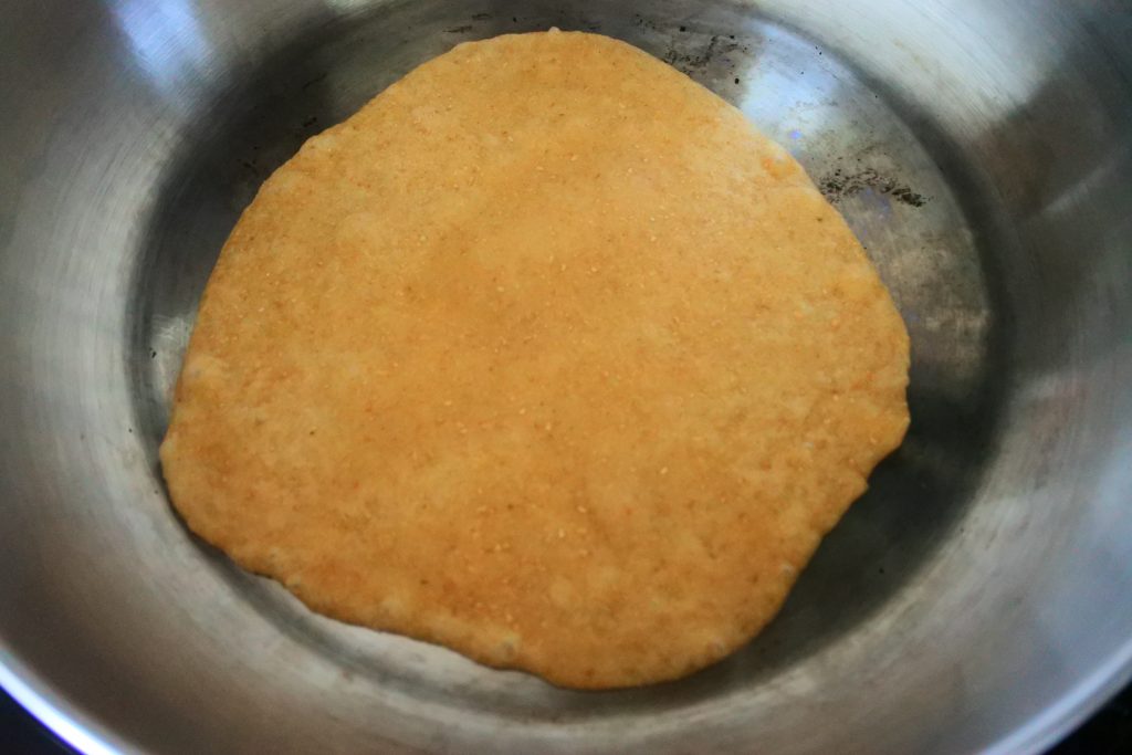 Overhead image of a whole wheat flour tortilla being cooked in a pan